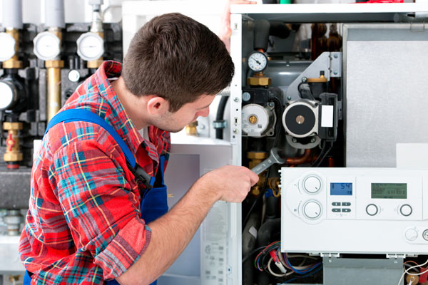 HVAC technician inspecting and repairing boiler controls in Sandy