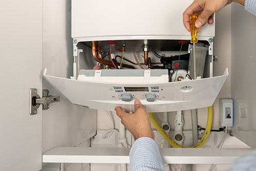 HVAC technician repairing an indoor boiler in Sandy