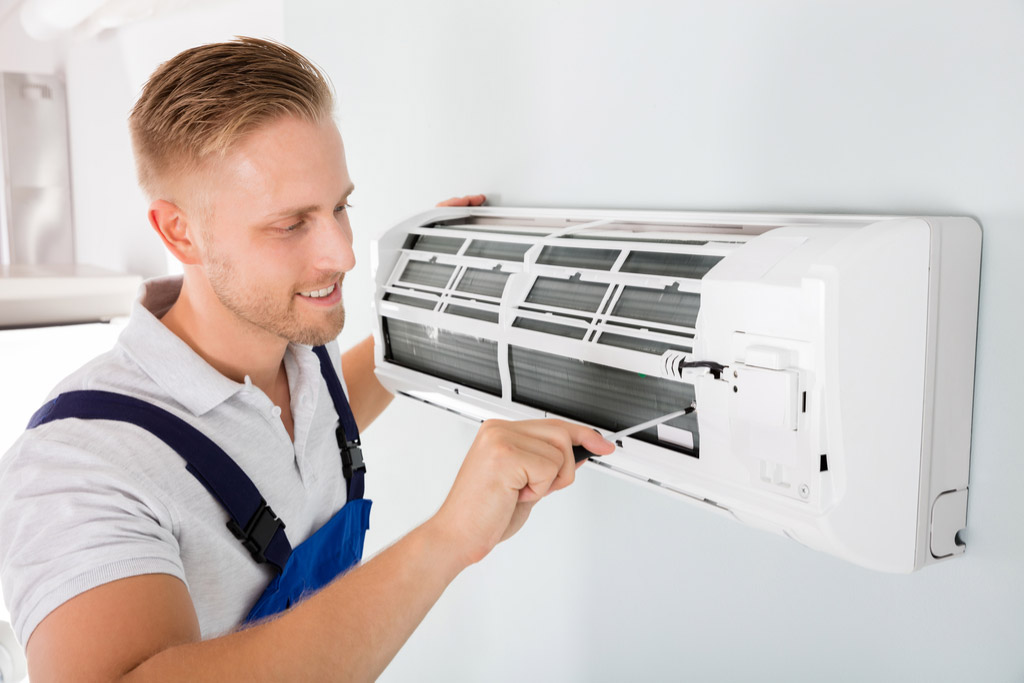 HVAC technician performing ductless air conditioning maintenance in Sandy
