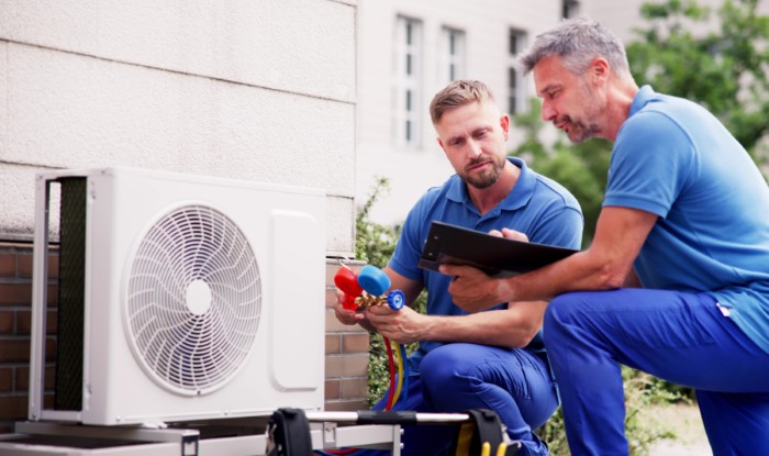 HVAC technicians installing an outdoor air conditioning unit in Sandy