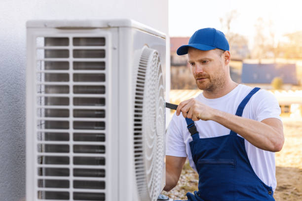 HVAC technician servicing an outdoor air conditioning unit in Sandy