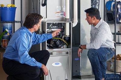 65df8c11f3e4c468cbd351a5_furnace repair vs replacement – Copy HVAC technician explaining furnace repair and maintenance to a homeowner in Sandy, UT