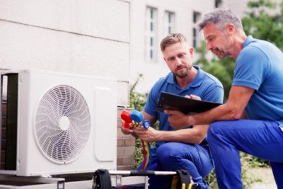 ac-installation-in-claremont-ca HVAC technicians reviewing an outdoor air conditioning unit in Sandy, UT